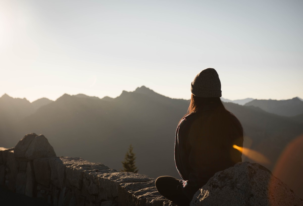 Person wearing knit cap and facing the mountains