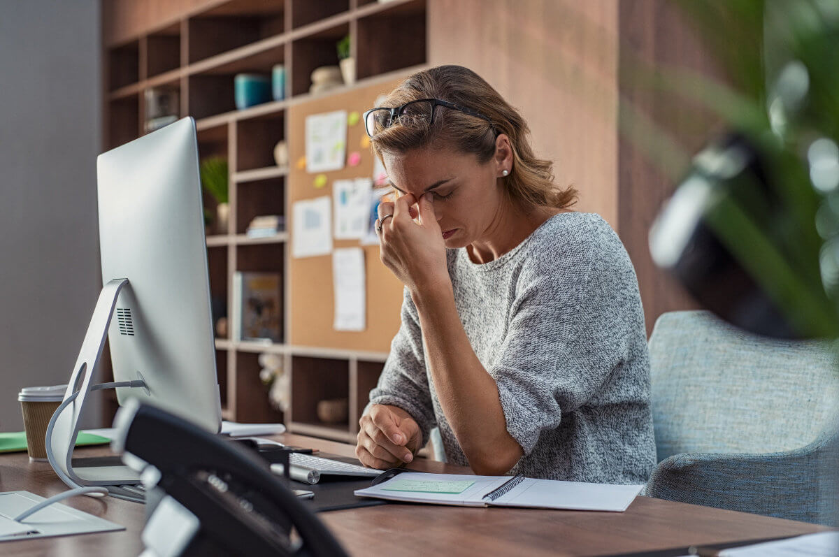 A woman with her hand pinching the bridge of her nose looking frustrated