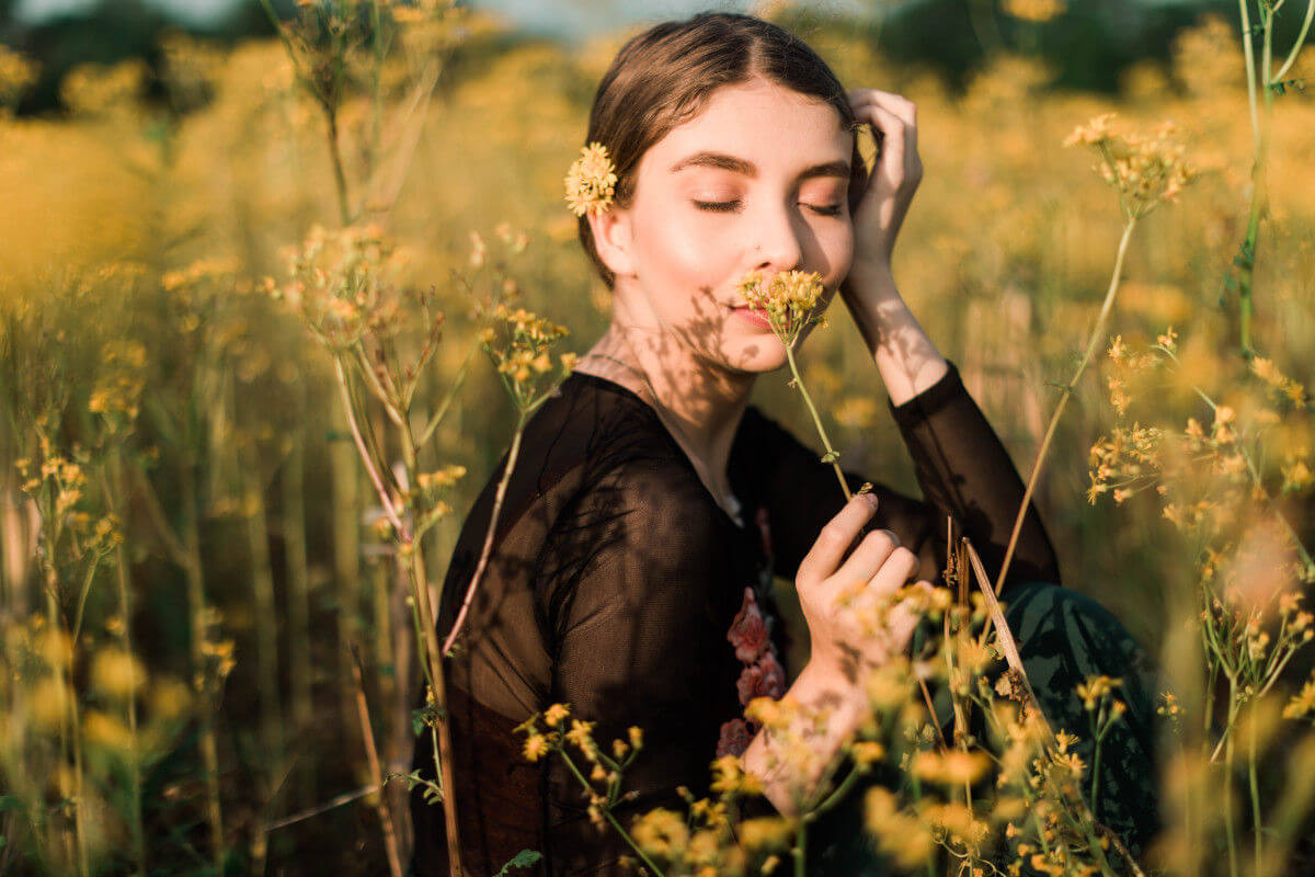 A woman smelling yellow flower in a field