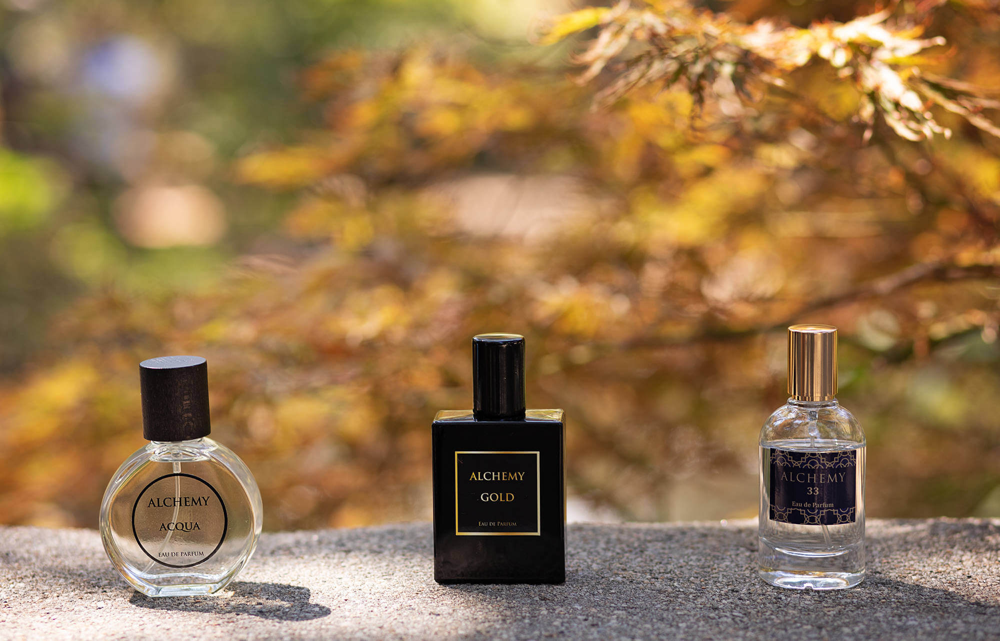 Close up of three Alchemy Perfumes products: Alchemy Acqua, Alchemy Gold, and Alchemy 33